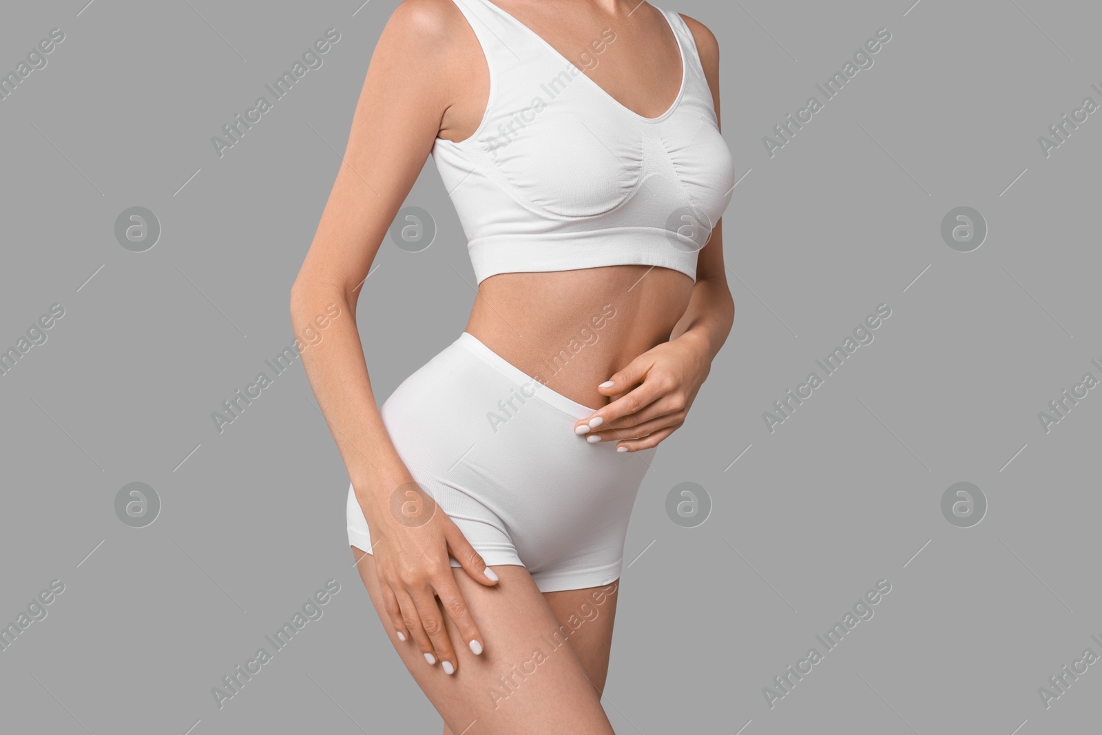 Photo of Slim woman with perfect skin in underwear on grey background, closeup. Body care