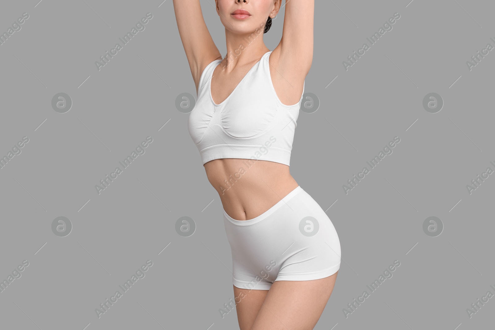 Photo of Slim woman with perfect skin in underwear on grey background, closeup. Body care