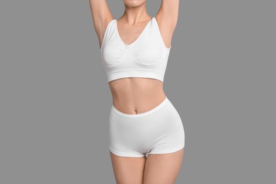 Photo of Slim woman with perfect skin in underwear on grey background, closeup. Body care