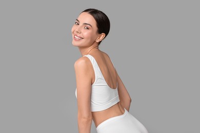 Photo of Smiling woman with perfect skin in underwear on grey background. Body care