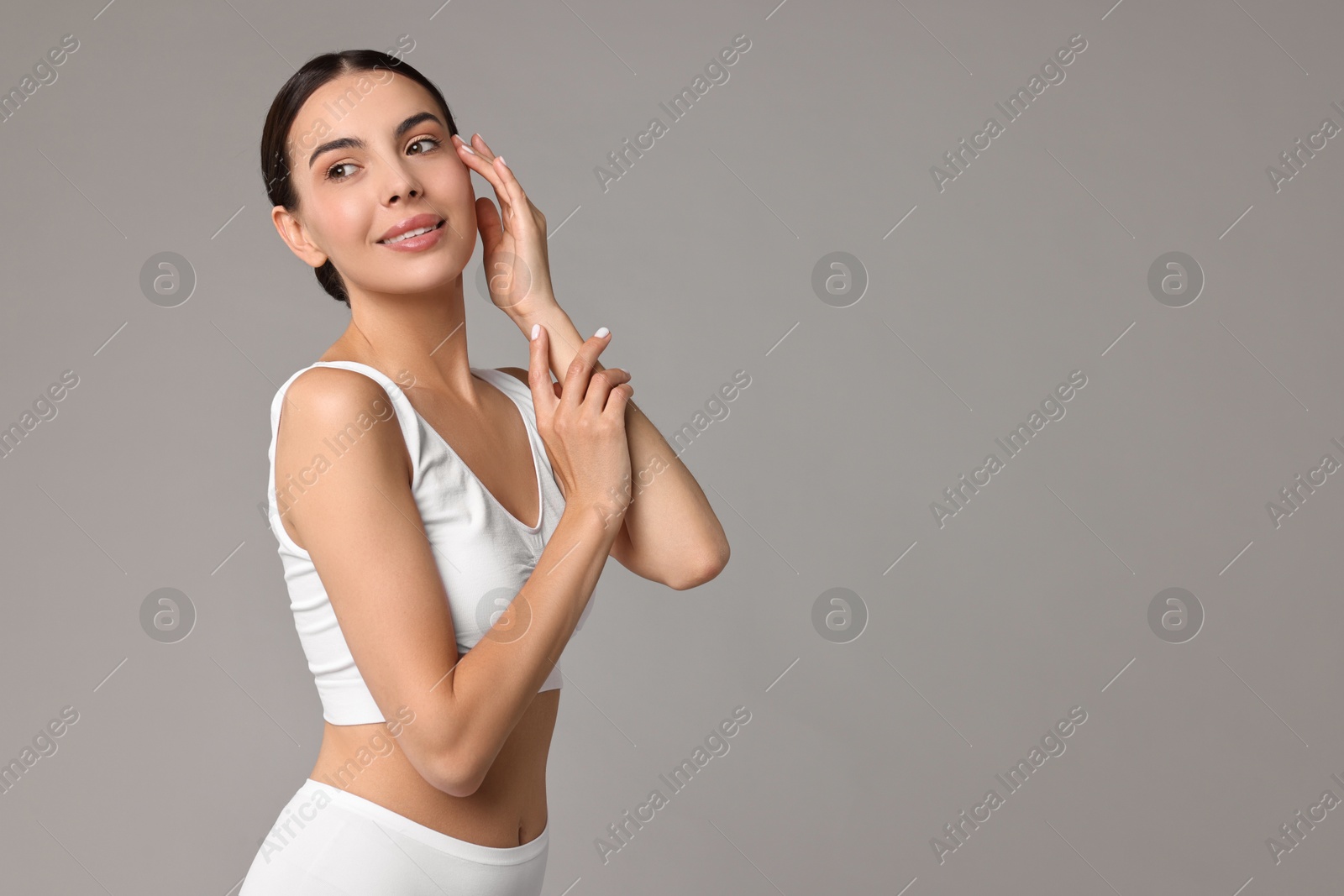 Photo of Smiling woman with perfect skin in underwear on grey background, space for text. Body care