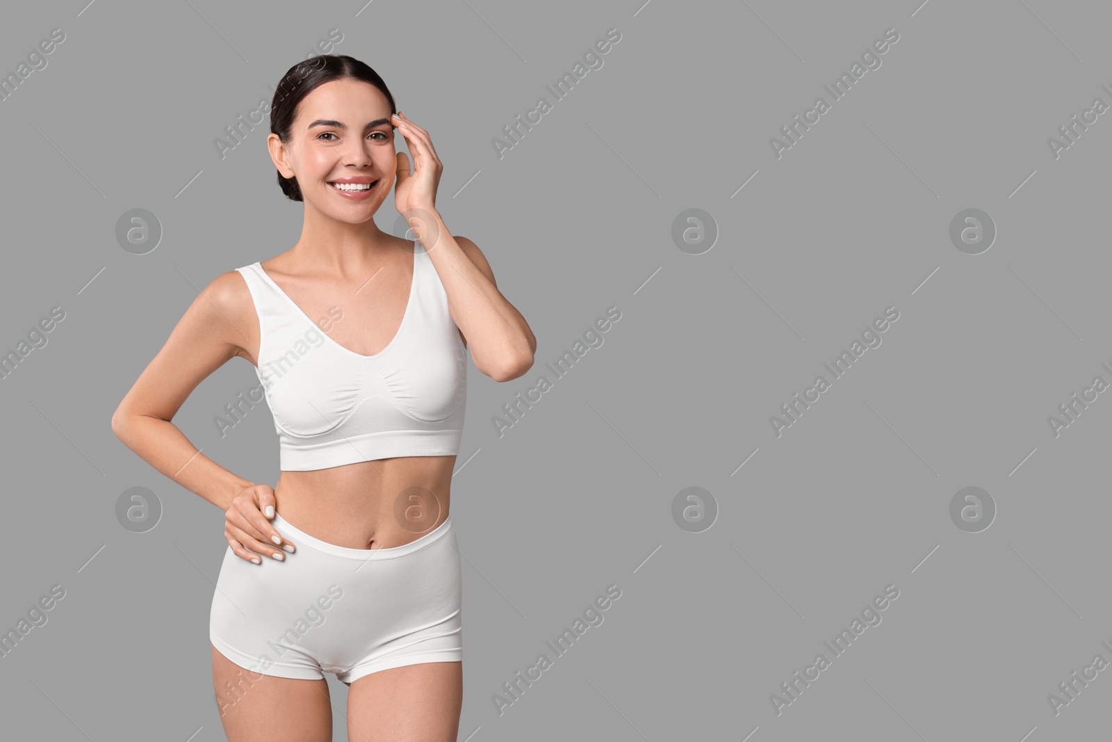 Photo of Smiling woman with perfect skin in underwear on grey background, space for text. Body care