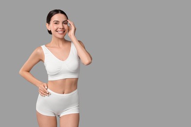 Photo of Smiling woman with perfect skin in underwear on grey background, space for text. Body care