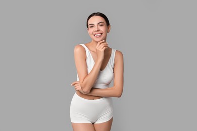 Photo of Smiling woman with perfect skin in underwear on grey background. Body care