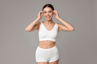 Photo of Smiling woman with perfect skin in underwear on grey background. Body care