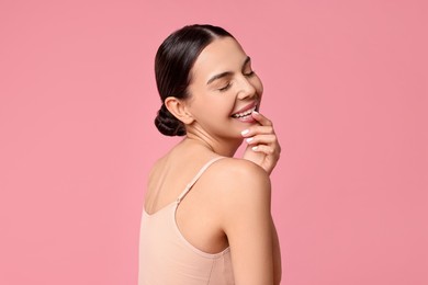 Photo of Smiling woman with perfect skin on pink background. Body care