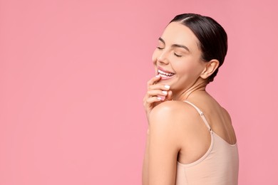 Photo of Smiling woman with perfect skin on pink background, space for text. Body care