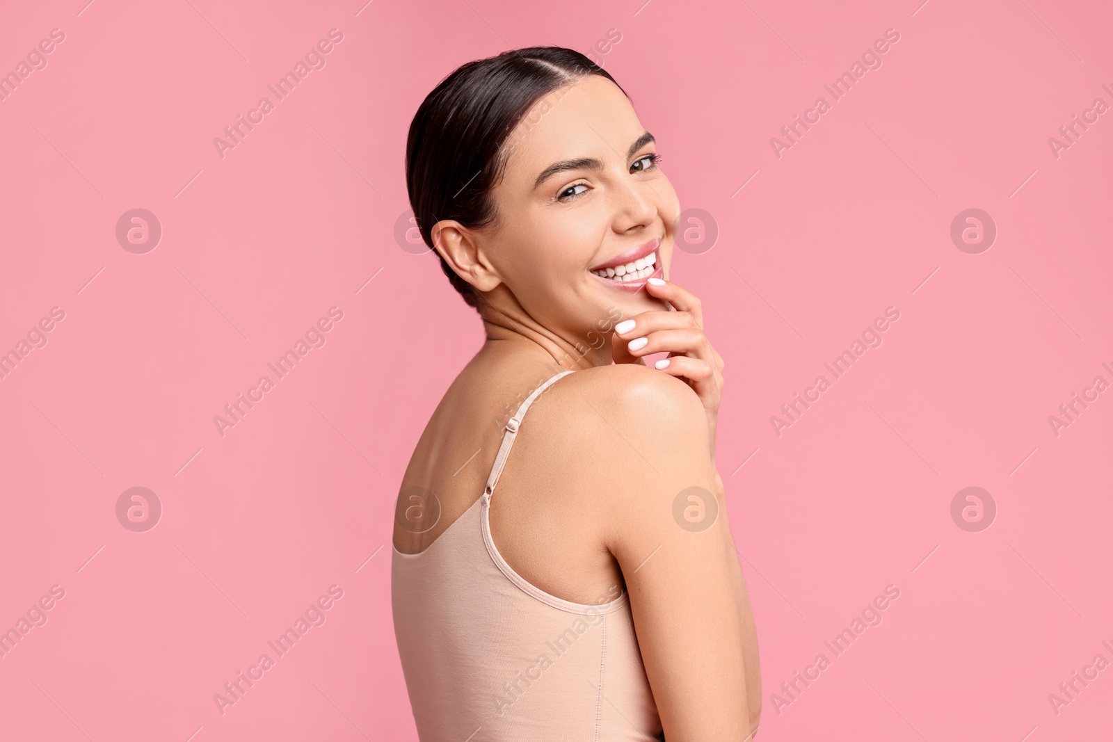 Photo of Smiling woman with perfect skin on pink background. Body care