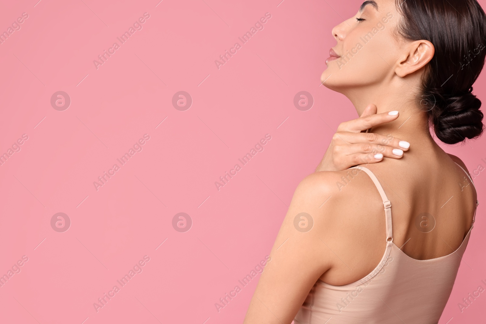 Photo of Beautiful woman with perfect skin on pink background, back view with space for text. Body care