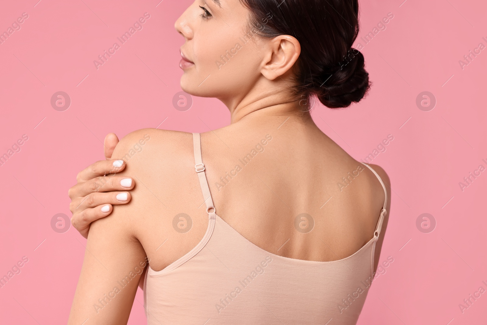 Photo of Beautiful woman with perfect skin on pink background, back view. Body care