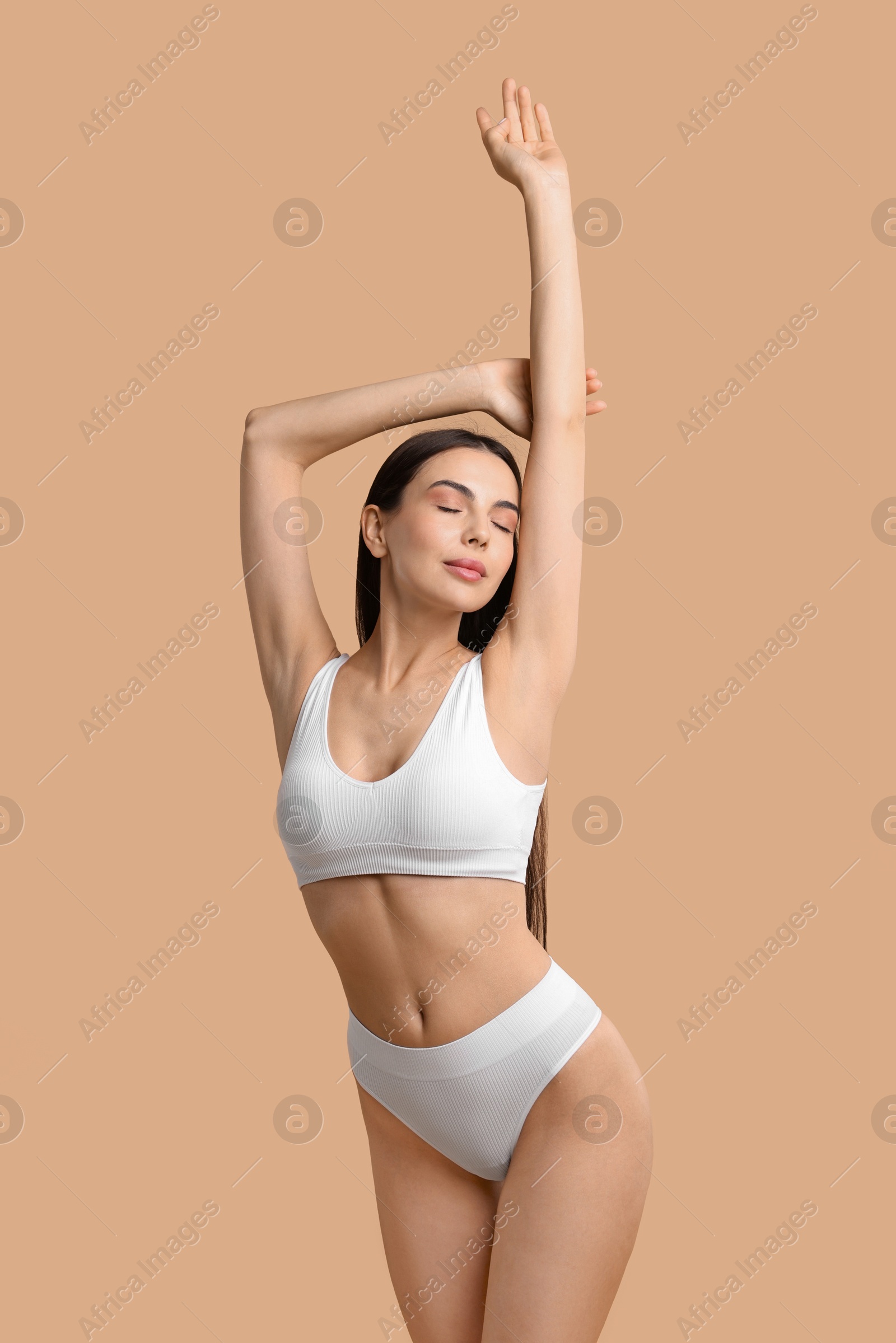 Photo of Beautiful woman with perfect skin in underwear posing on beige background. Body care