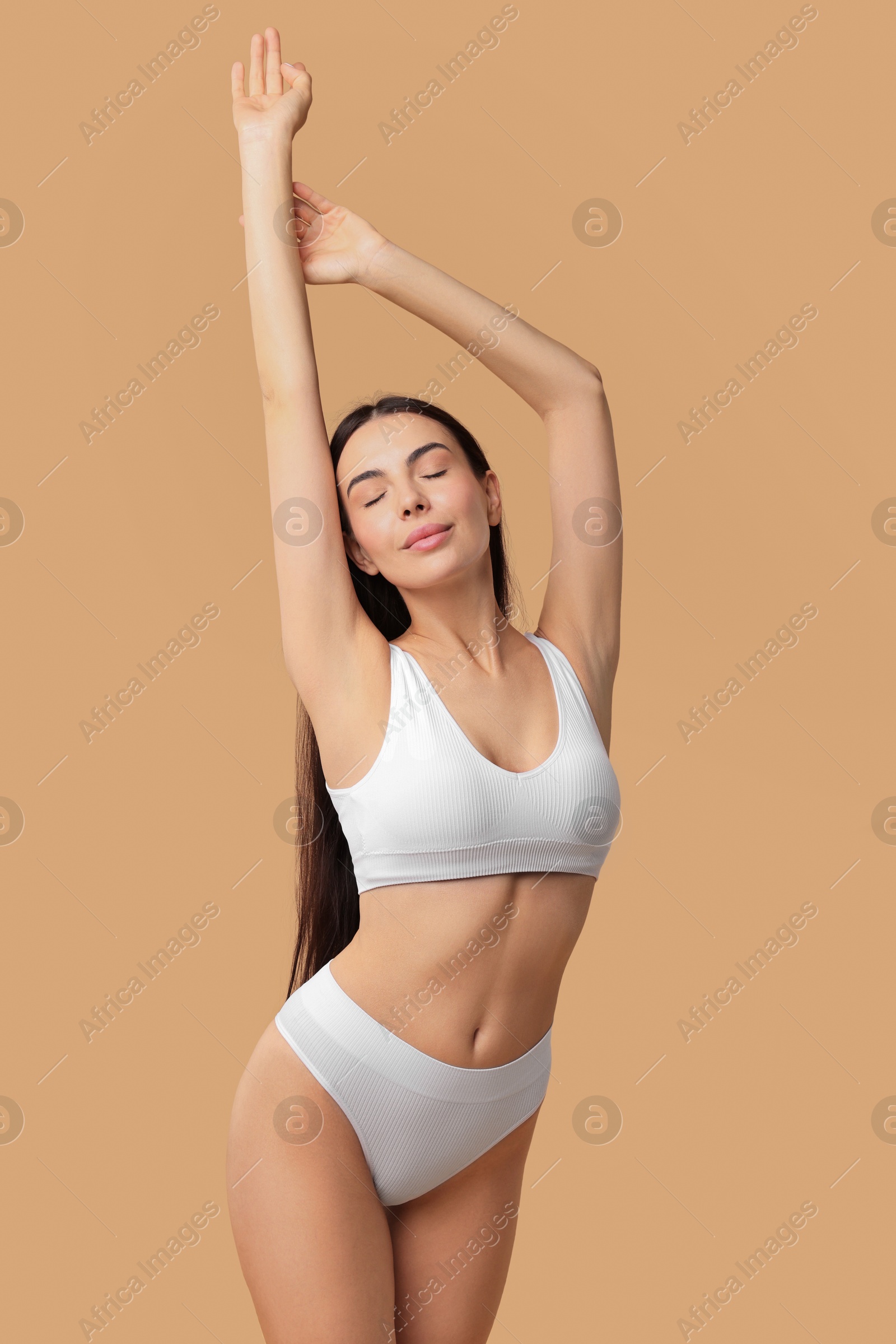 Photo of Beautiful woman with perfect skin in underwear posing on beige background. Body care