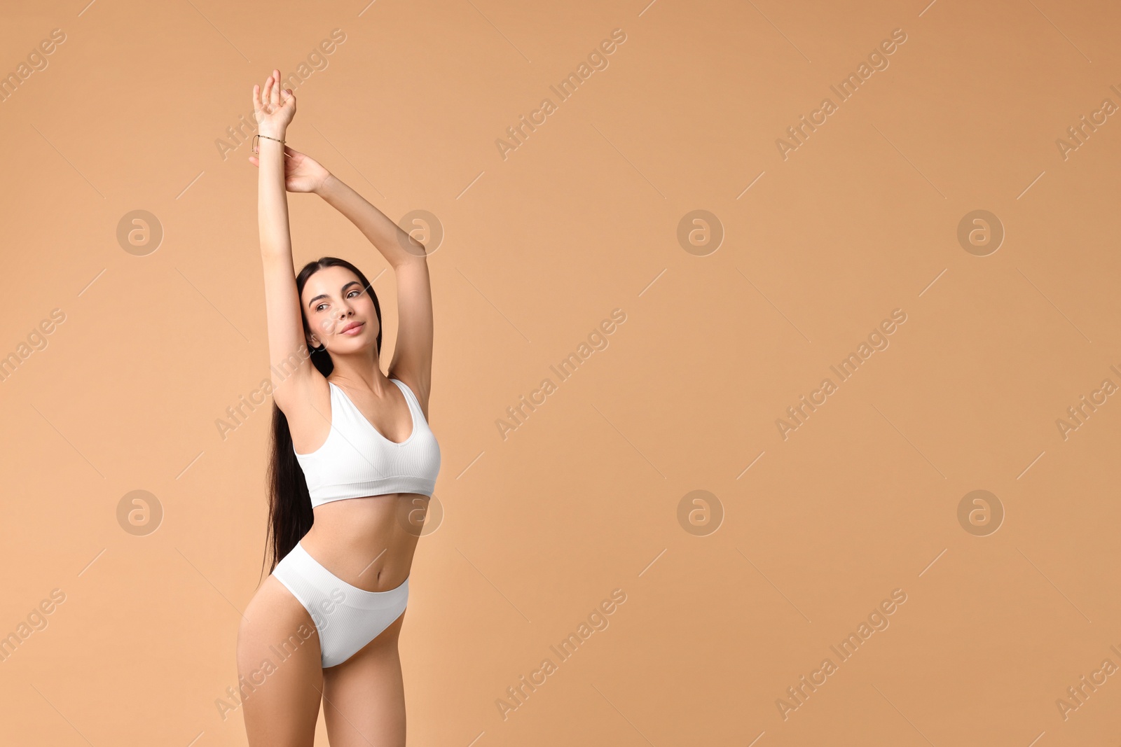 Photo of Beautiful woman with perfect skin in underwear posing on beige background, space for text. Body care