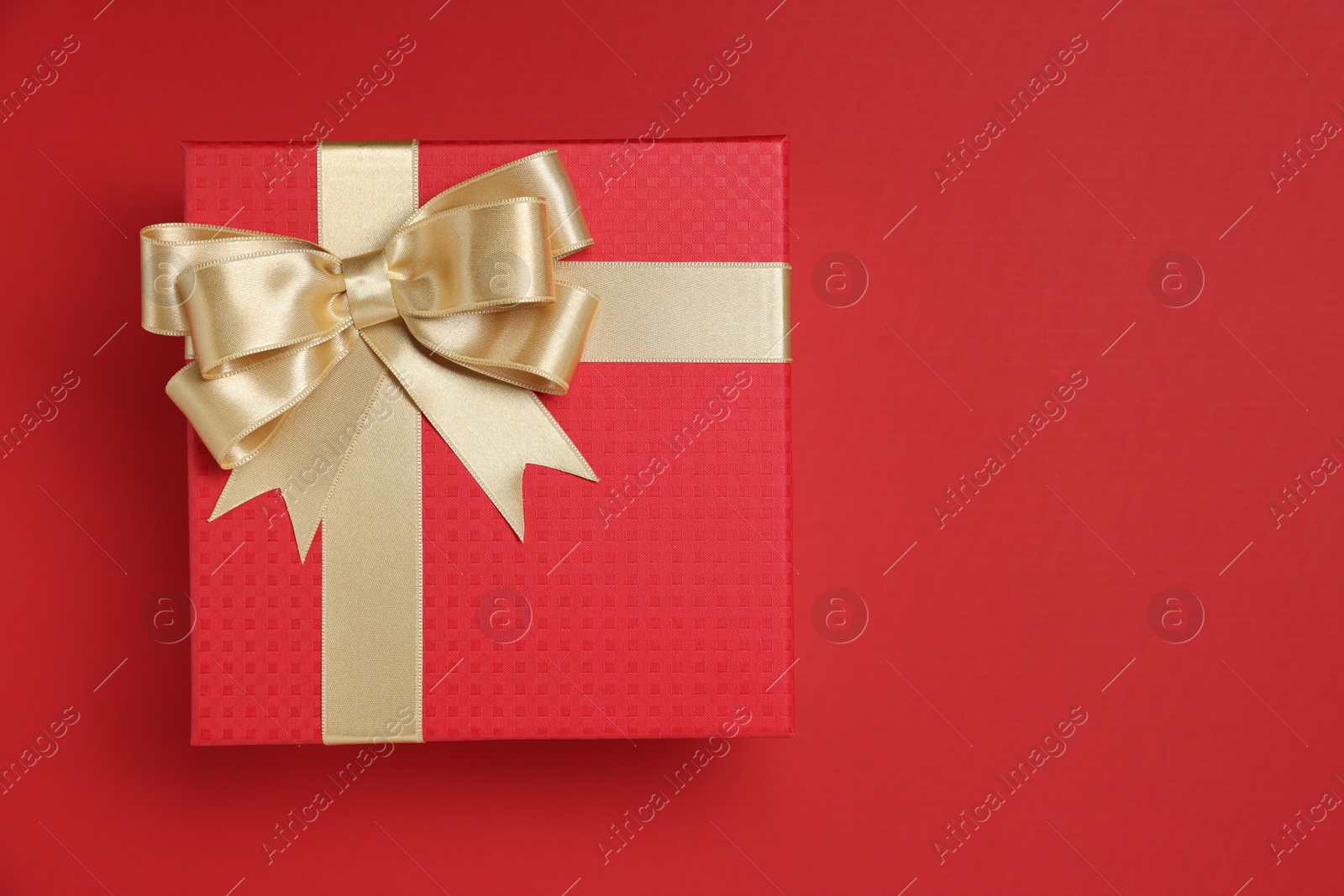 Photo of Gift box with bow on red background, top view. Space for text