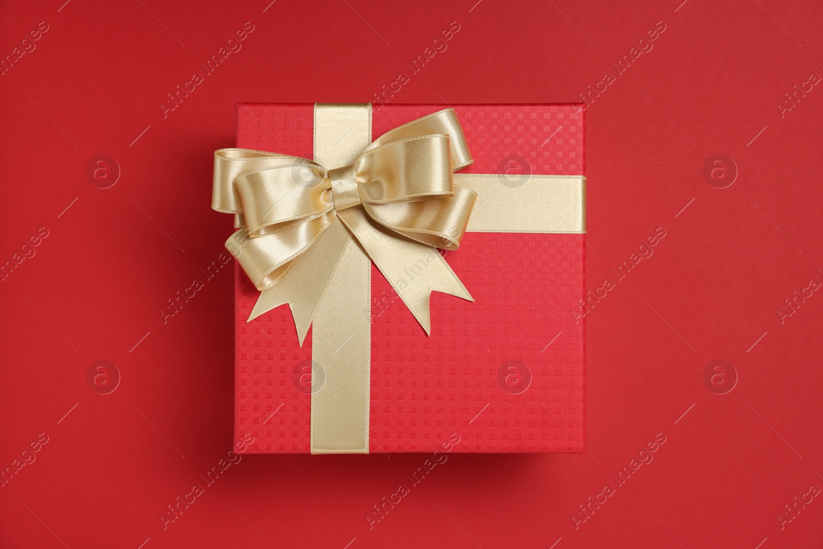 Photo of Gift box with bow on red background, top view