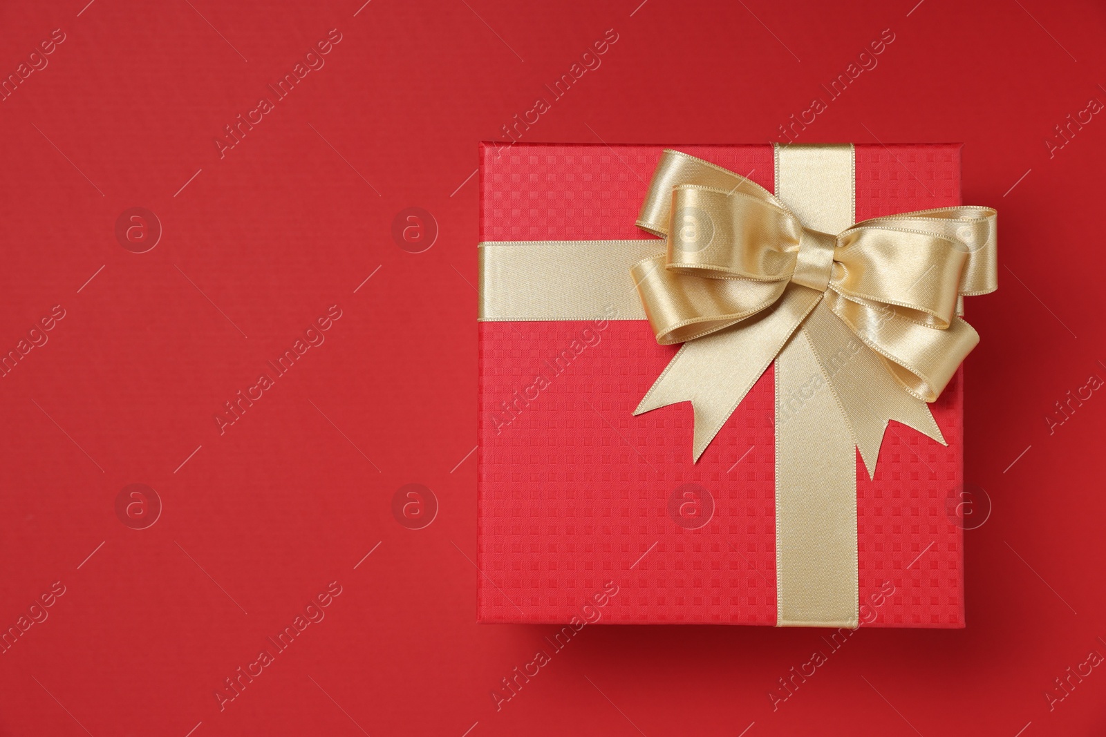 Photo of Gift box with bow on red background, top view. Space for text