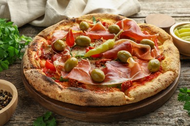 Tasty pizza and ingredients on wooden table