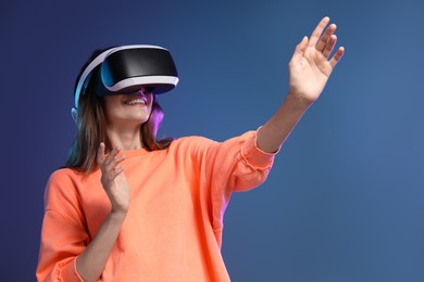 Photo of Smiling woman using virtual reality headset on dark blue background