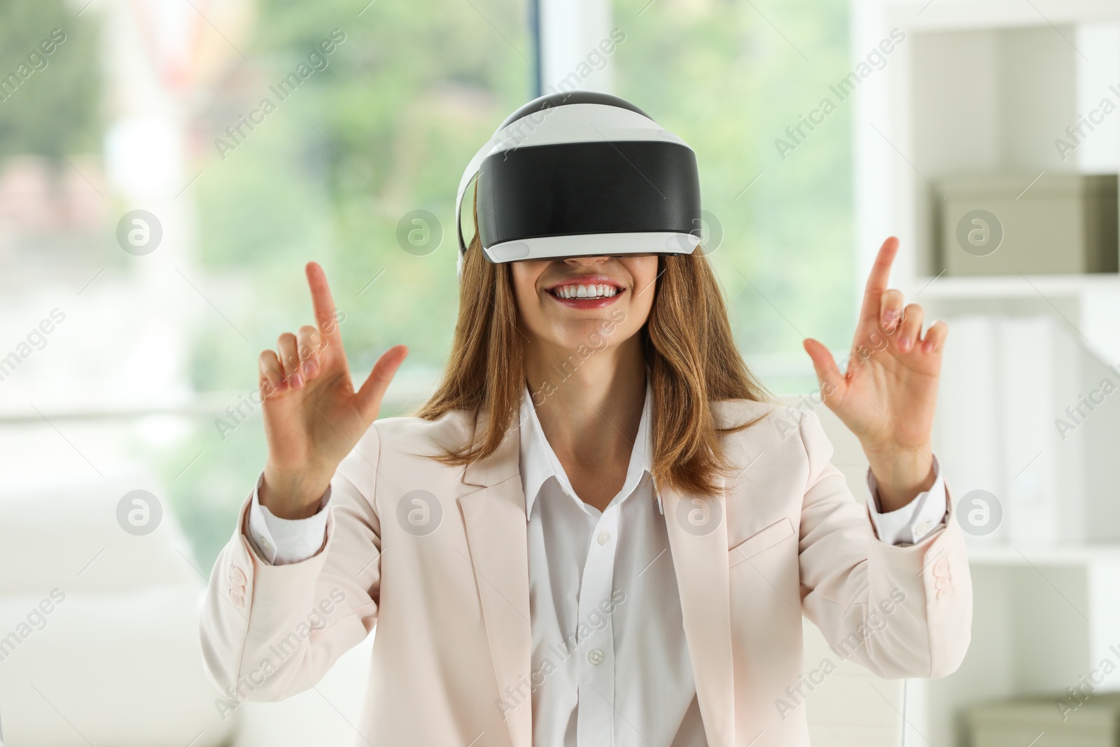 Photo of Smiling woman using virtual reality headset in office