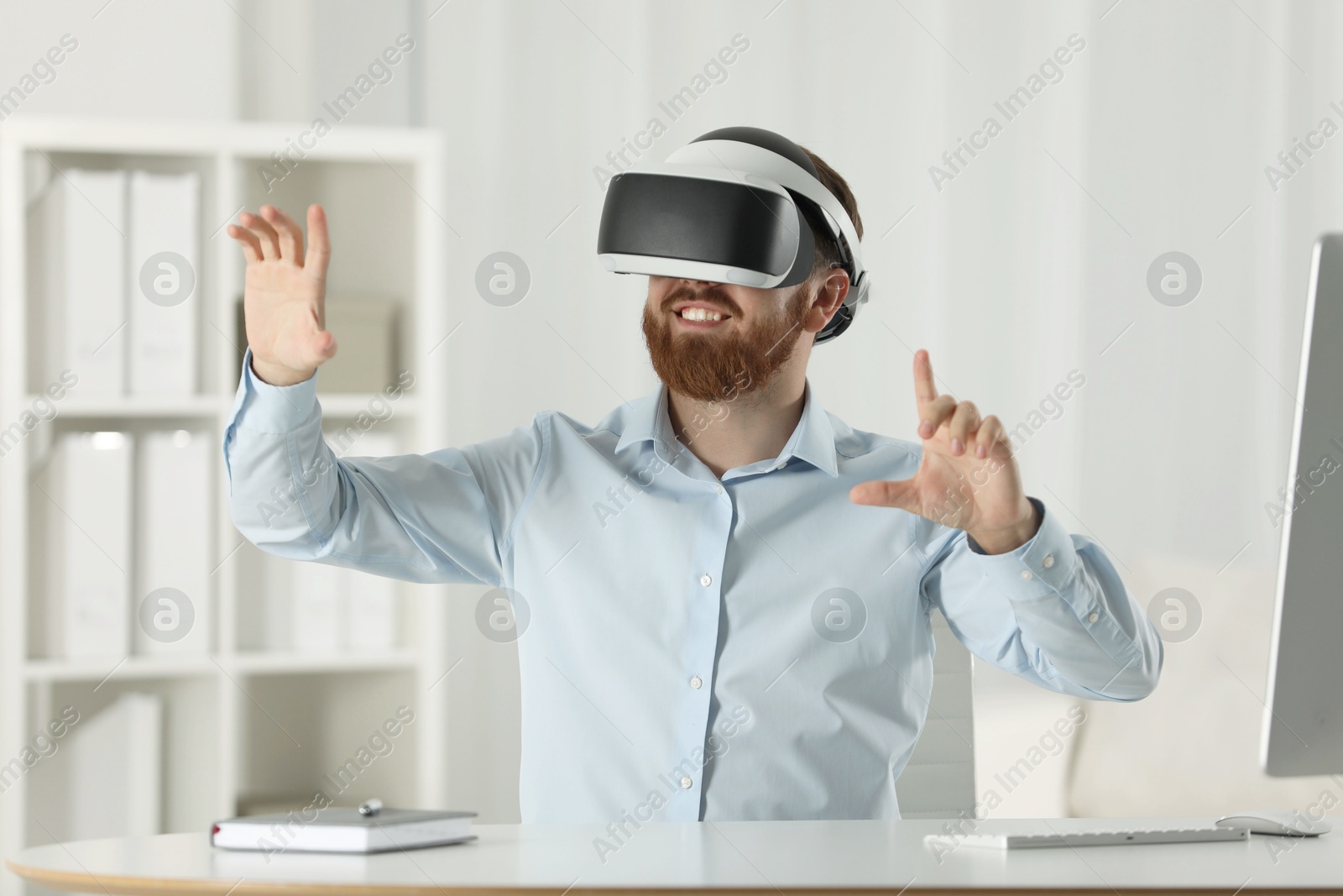 Photo of Smiling man using virtual reality headset at workplace in office