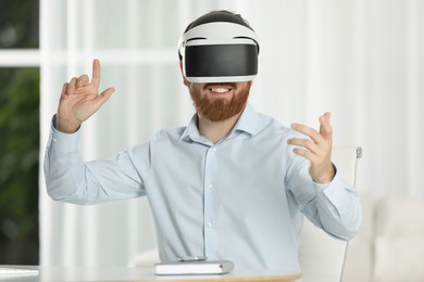 Photo of Smiling man using virtual reality headset at workplace in office