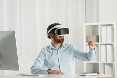 Photo of Man using virtual reality headset at workplace in office