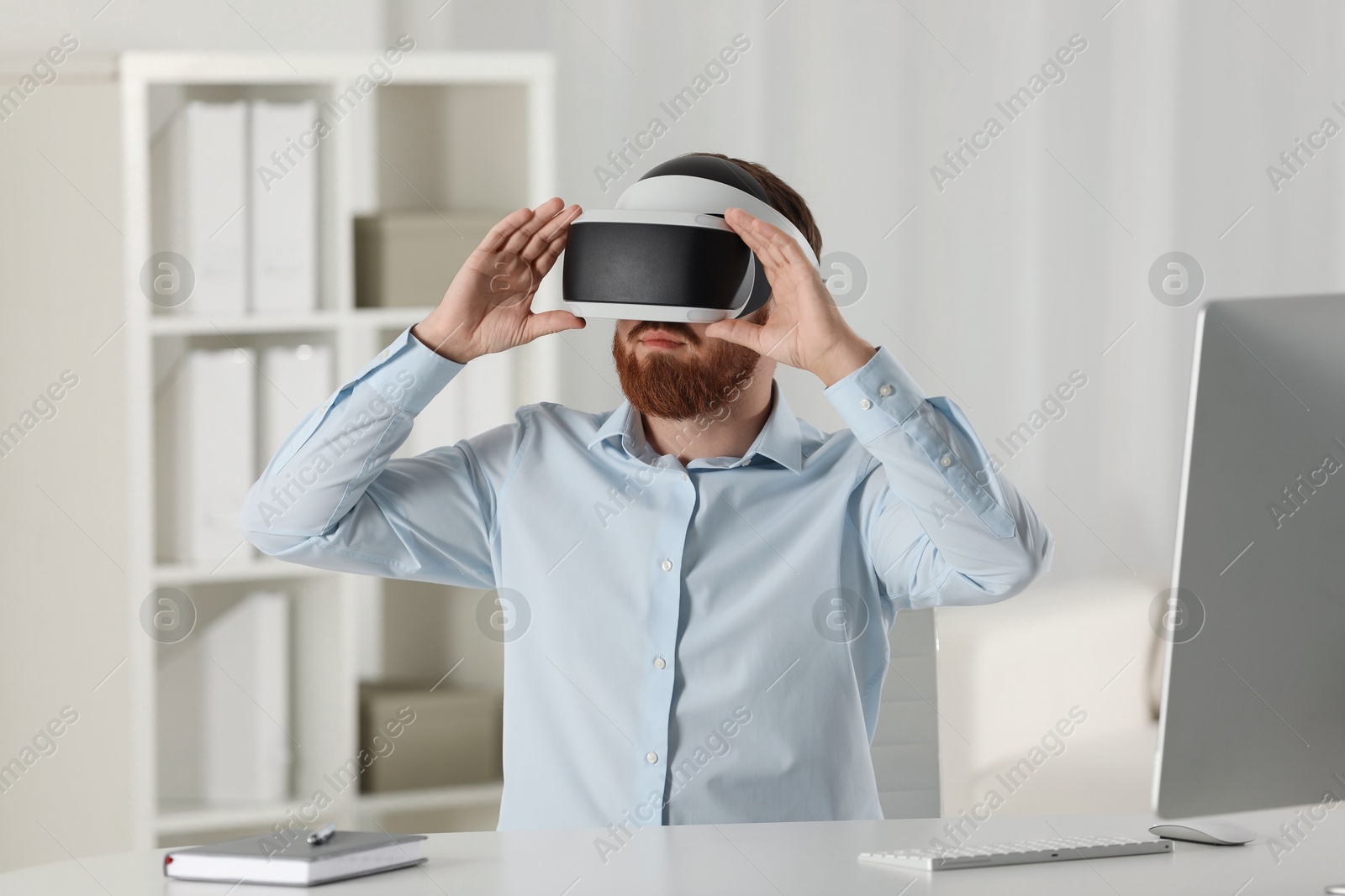 Photo of Man using virtual reality headset at workplace in office