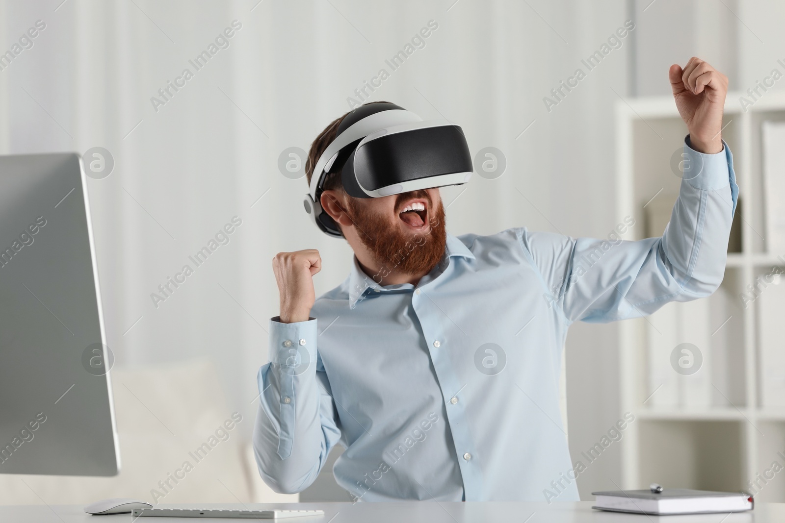 Photo of Emotional man using virtual reality headset at workplace in office