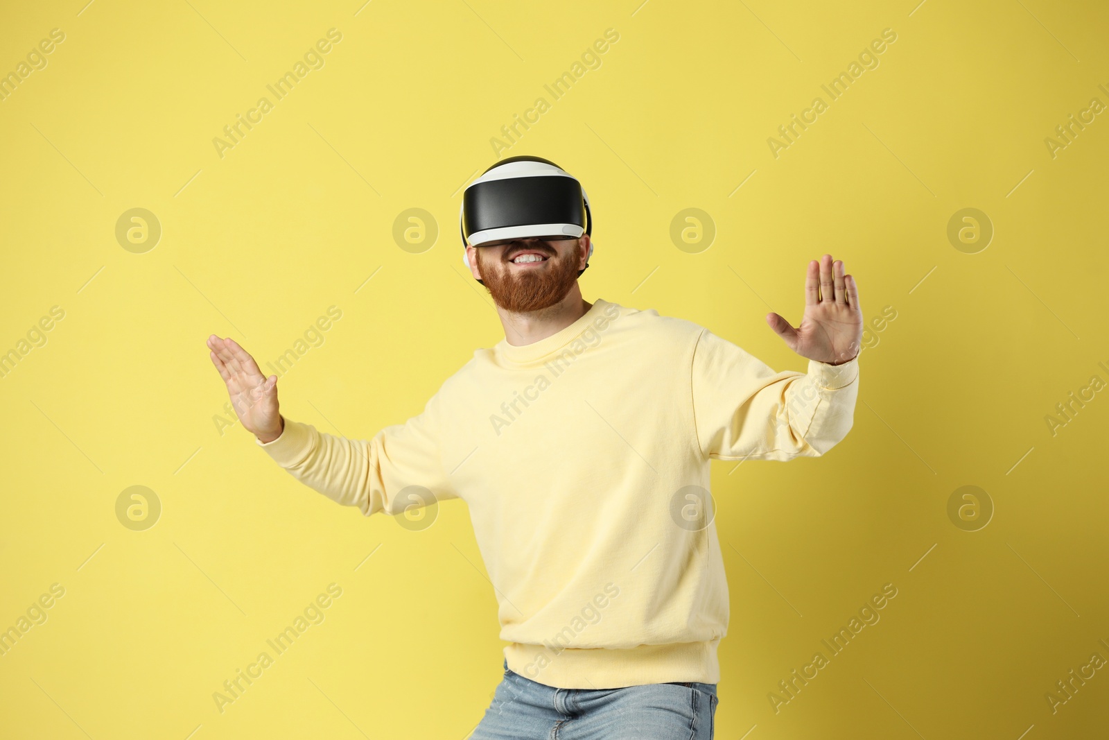 Photo of Man using virtual reality headset on pale yellow background