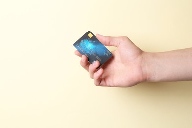 Man holding credit card on pale yellow background, closeup