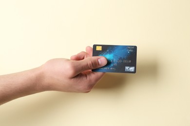 Man holding credit card on pale yellow background, closeup