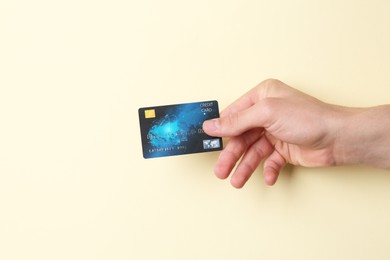 Man holding credit card on pale yellow background, closeup