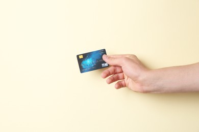 Photo of Man holding credit card on pale yellow background, closeup