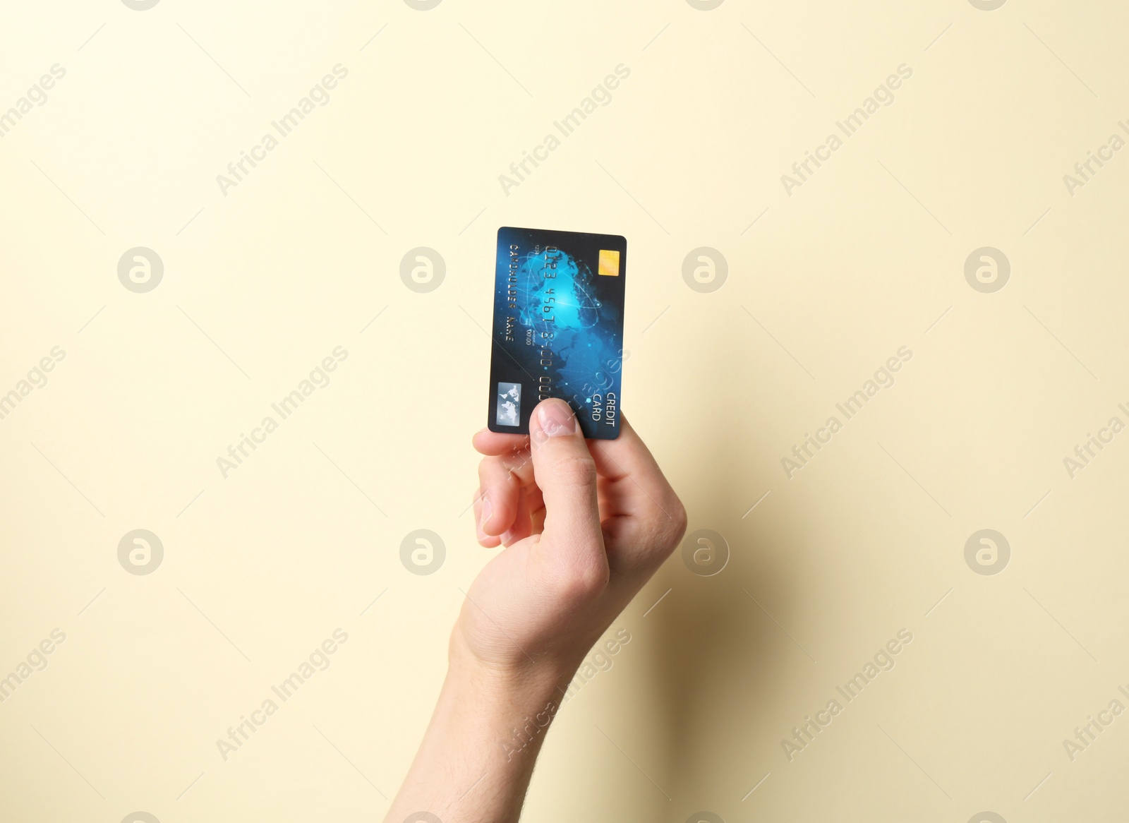 Photo of Man holding credit card on pale yellow background, closeup