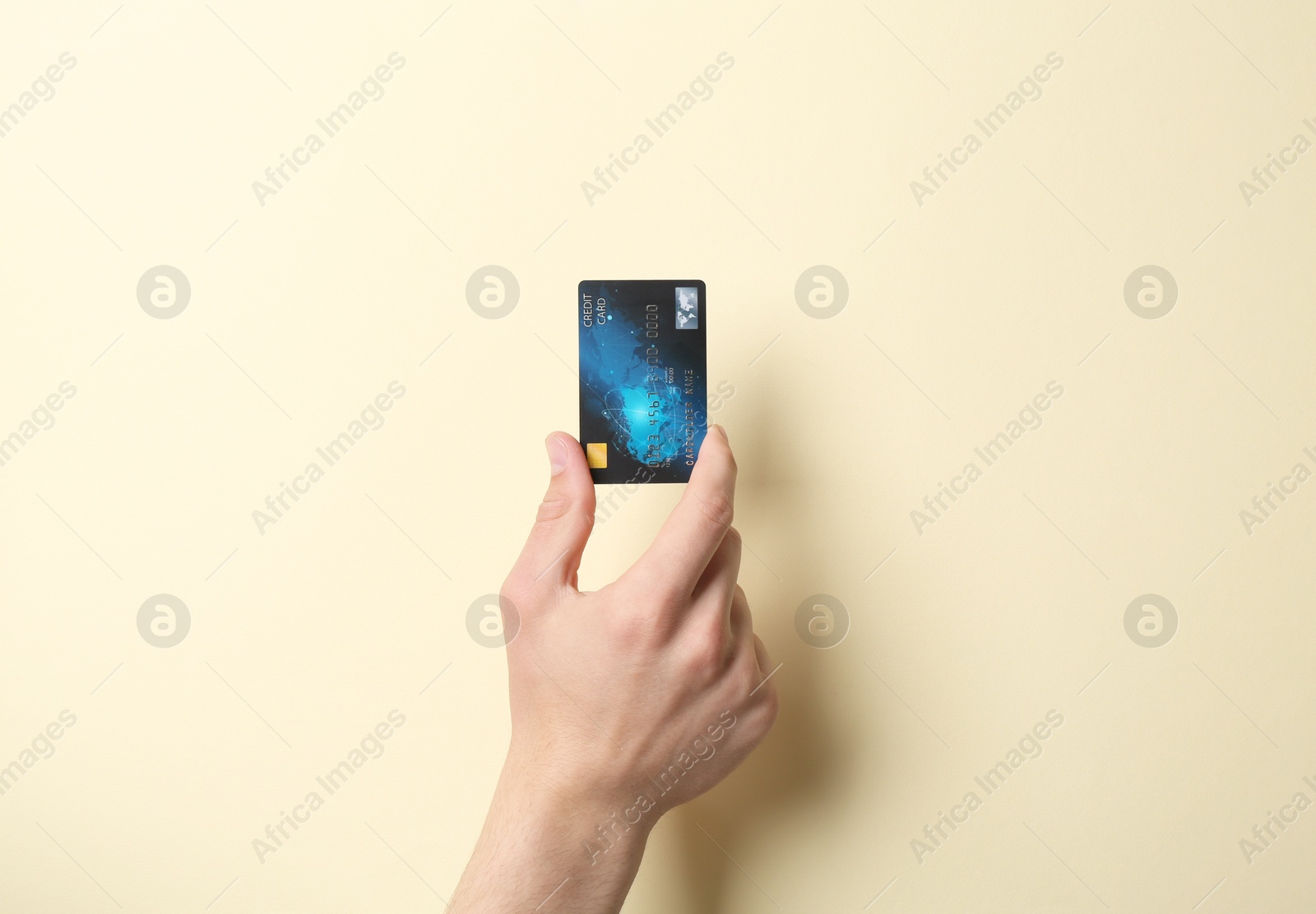 Photo of Man holding credit card on pale yellow background, closeup