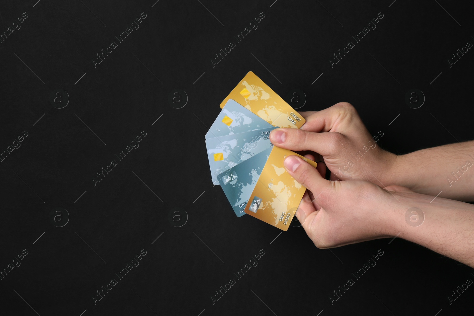 Photo of Man holding credit cards on black background, closeup