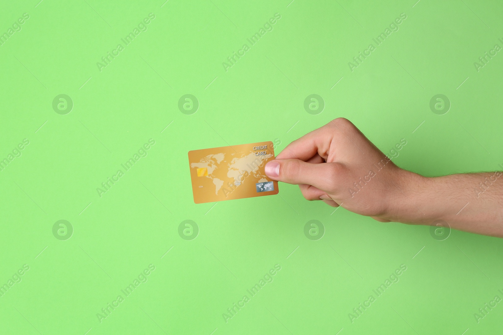 Photo of Man holding credit card on light green background, closeup