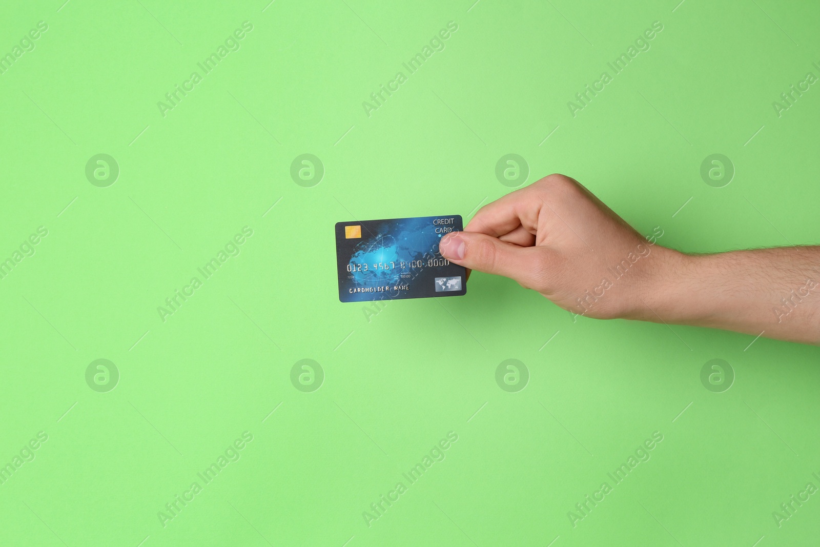 Photo of Man holding credit card on light green background, closeup