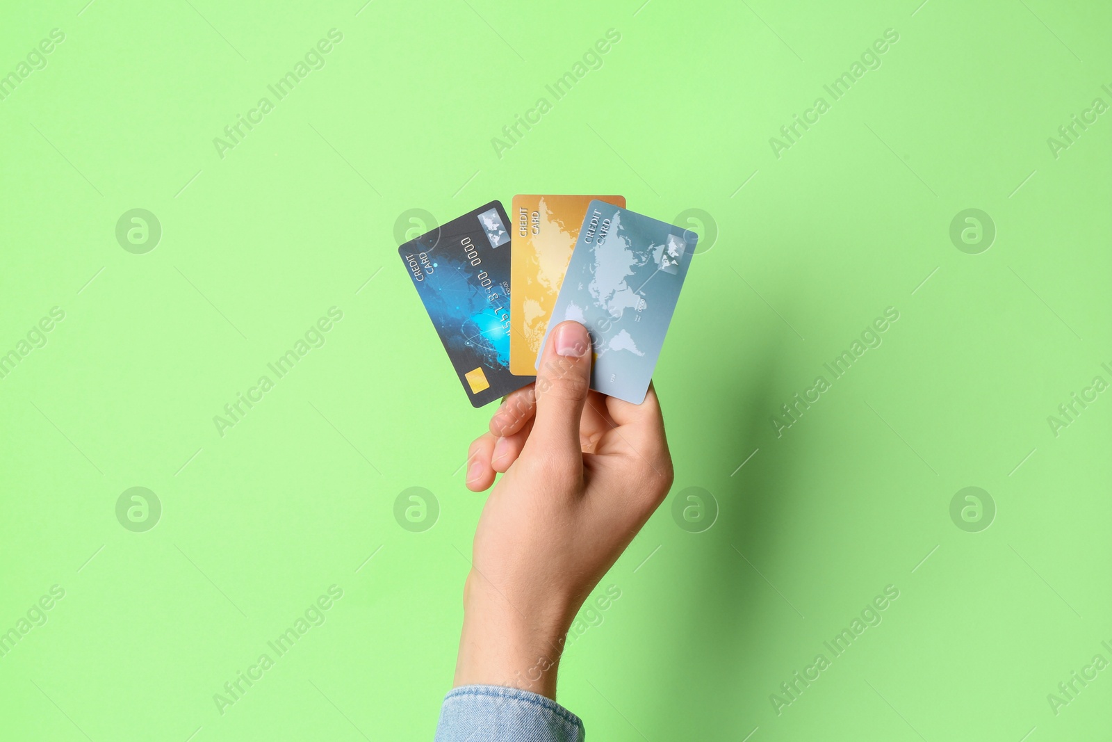 Photo of Man holding credit cards on light green background, closeup