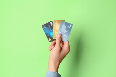 Man holding credit cards on light green background, closeup