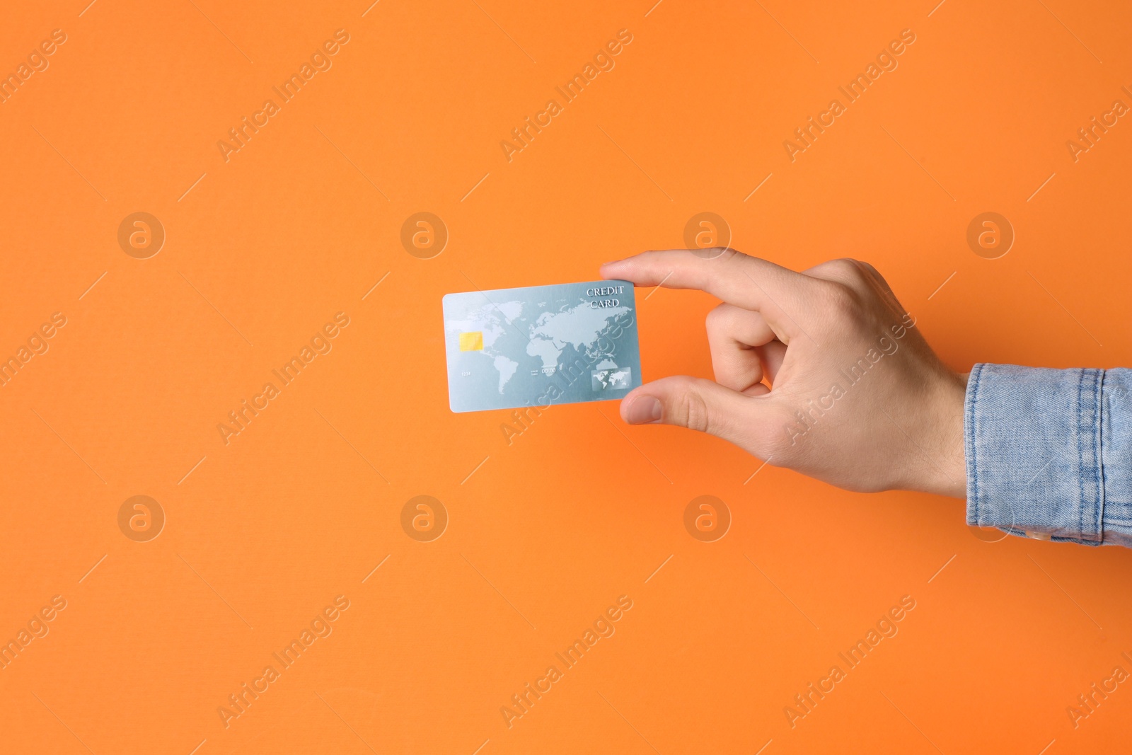 Photo of Man holding credit card on orange background, closeup