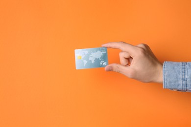 Photo of Man holding credit card on orange background, closeup