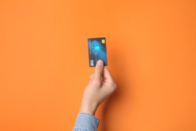 Man holding credit card on orange background, closeup