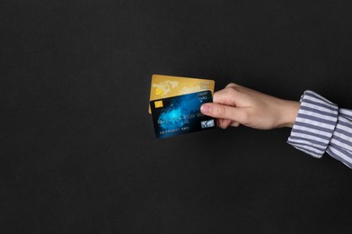 Photo of Woman holding credit cards on black background, closeup