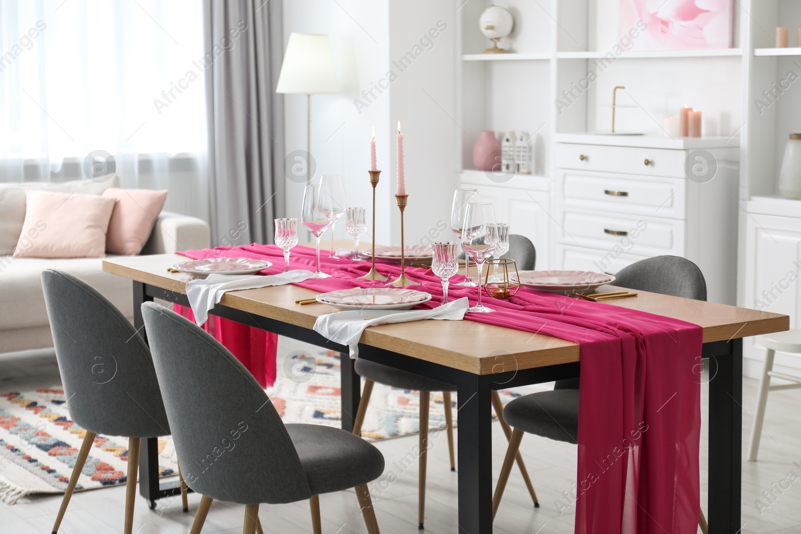 Photo of Beautiful table setting with burning candles and pink accent in dining room