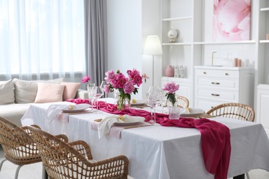 Photo of Beautiful table setting with pink accent and rattan chairs in dining room