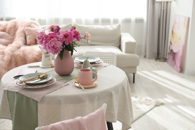 Photo of Beautiful table setting with pink peonies in living room. Space for text