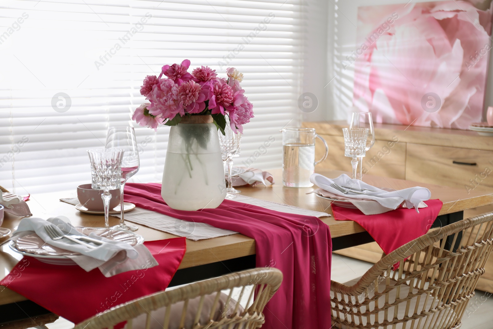 Photo of Pink peonies on table with beautiful setting and rattan chairs in dining room