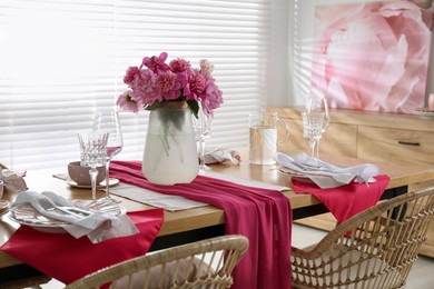 Photo of Pink peonies on table with beautiful setting and rattan chairs in dining room