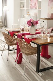 Photo of Pink peonies on table with beautiful setting and rattan chairs in dining room